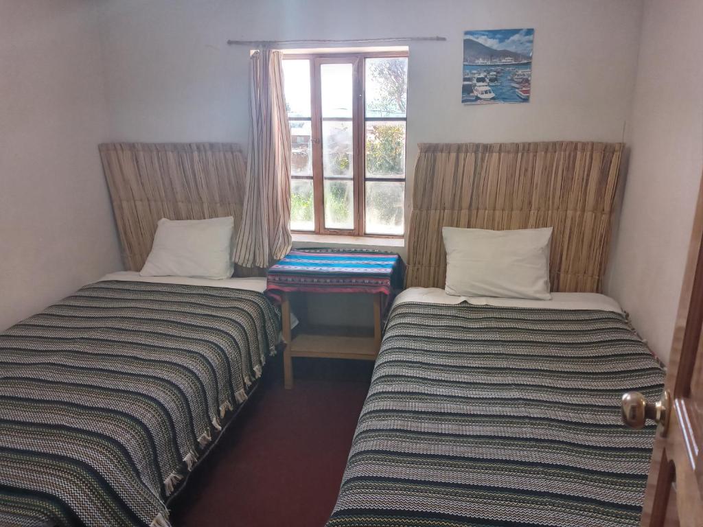 two beds sitting in a room with a window at Hospedaje jatari in Estanciasuyo