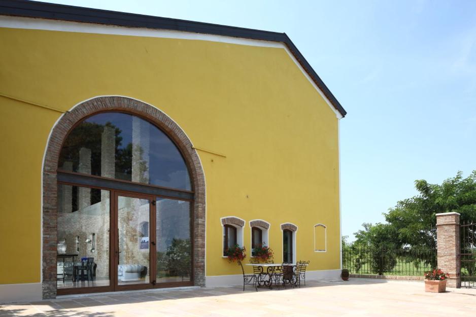 a yellow building with a large window and tables at Agriturismo Corte Capiluppia in Curtatone