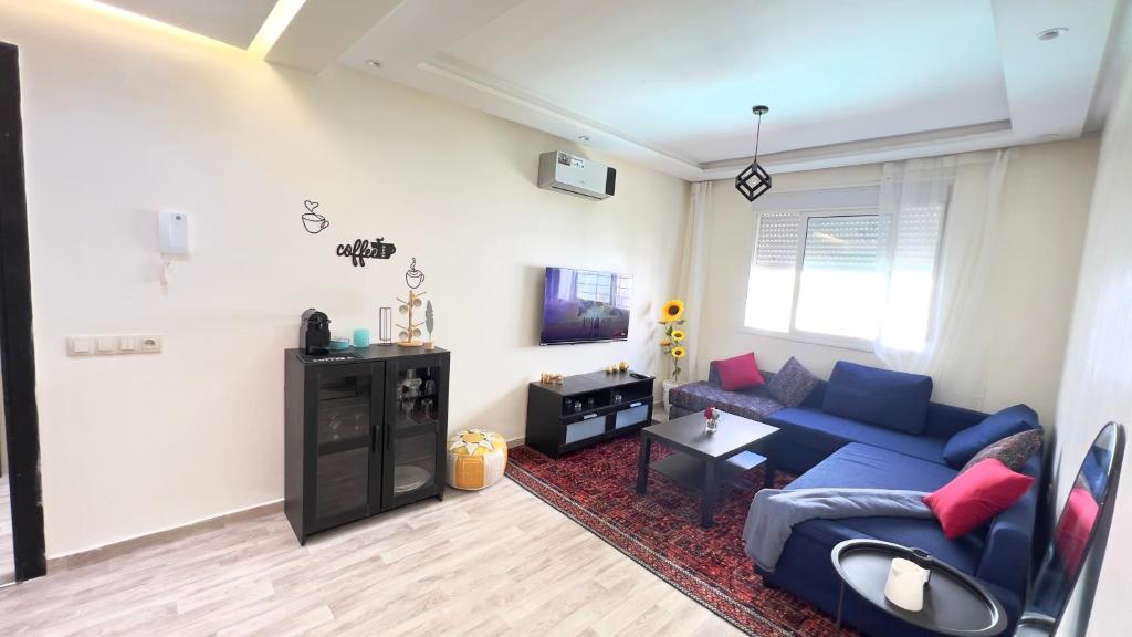 a living room with a blue couch and a table at Perle de Tamaris Appartement Moderne, Bien Équipé, Piscine pour Enfants Parking in Casablanca