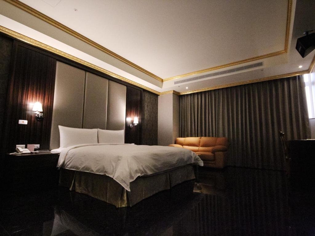 a hotel room with a bed and a chair at Gold Sand Hotel in Hsinchu City