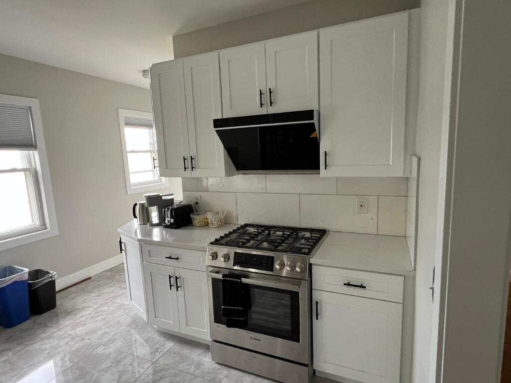 a kitchen with white cabinets and a stove top oven at Airport room with free parking in Boston