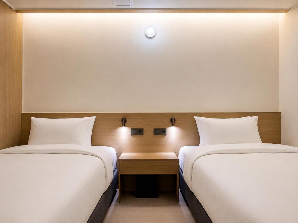 two beds sitting next to each other in a room at Link B Hotel in Busan