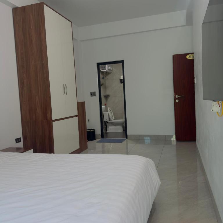a bedroom with a white bed and a bathroom at Queen Hotel in Thạch Cầu