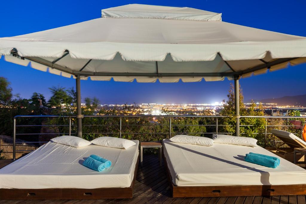 duas camas num deque com um guarda-chuva em Fuente de Ibiza em Sant Jordi
