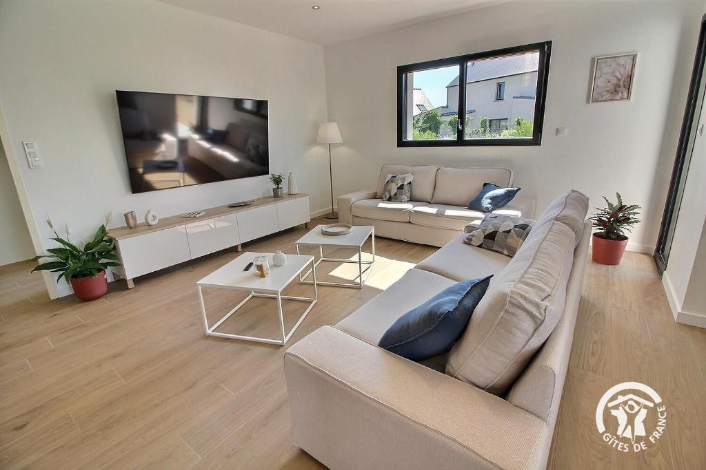 a living room with a couch and a tv at Enez bihan in Plougrescant