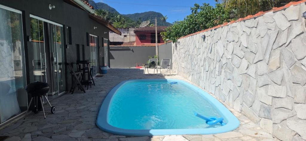 a blue swimming pool next to a stone wall at Arandura Chalés maresias 04 in São Sebastião