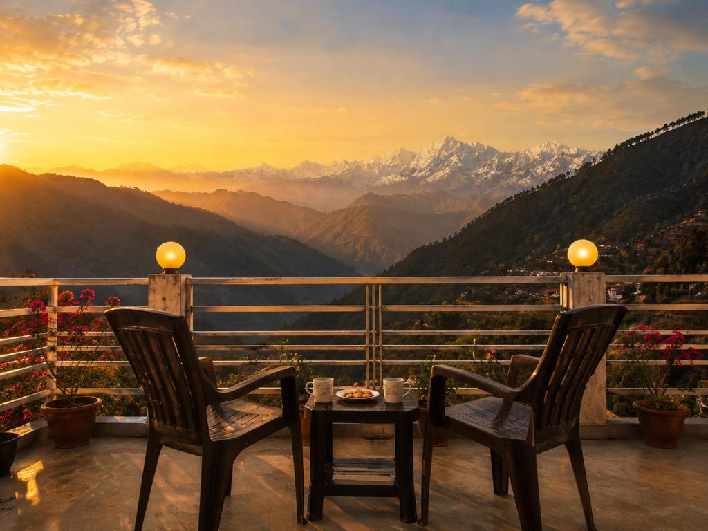a table and chairs on a balcony with a view of mountains at Hotel vidya om palace in Ukhimath