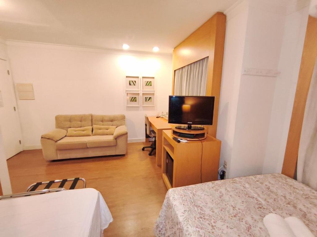 a living room with a television and a couch at Flat Aeroporto Congonhas in São Paulo
