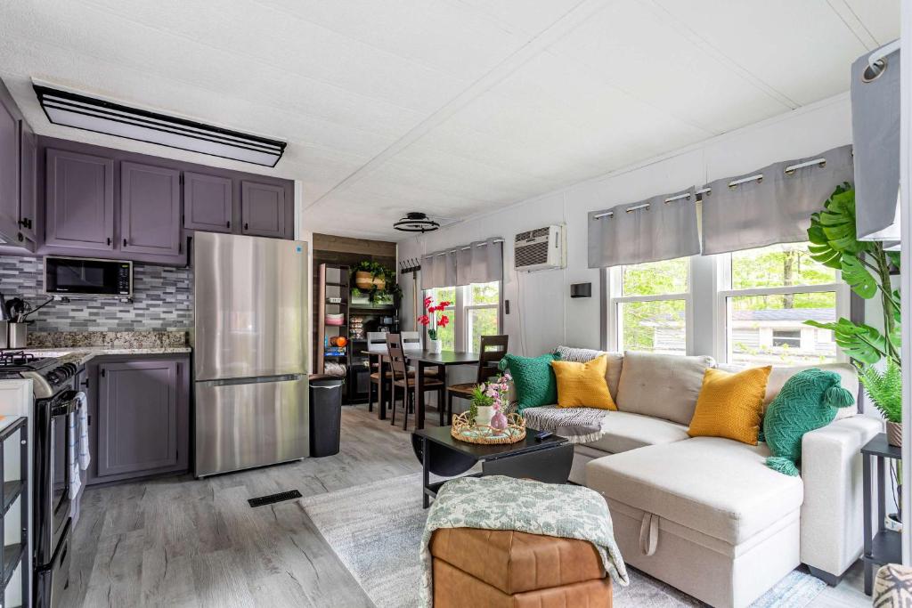 a living room with a white couch and a kitchen at The Cranny Tiny Home Fire Pit Close to Lake in Maple Lake