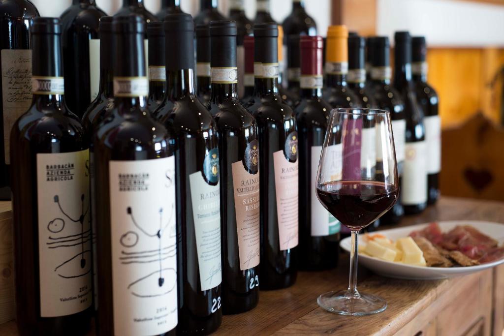 a bunch of wine bottles and a glass of wine at Albergo K2 in Madesimo