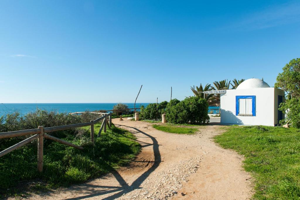 a dirt road next to a white building and the ocean at Litoral Mar Beside the Beach in Portimão