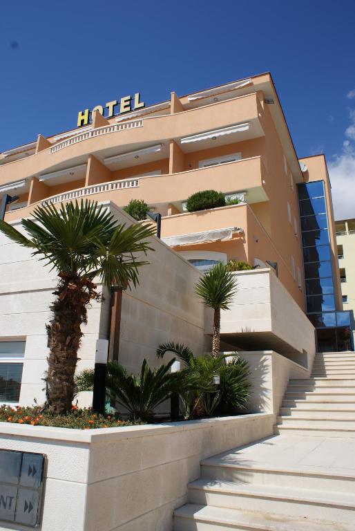 a building with stairs and palm trees in front of it at Hotel Rosina in Makarska