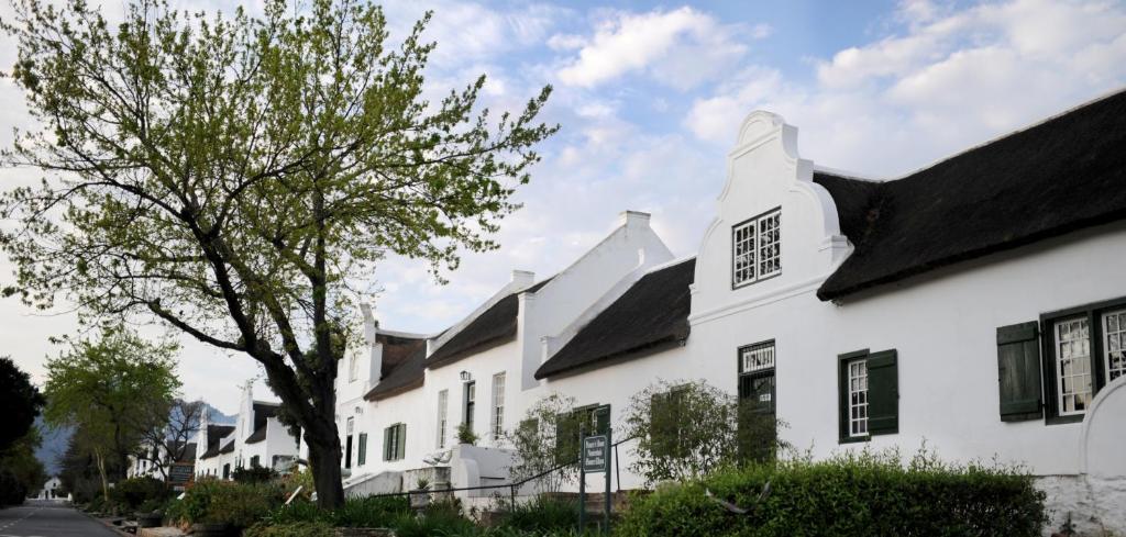 a white house with black windows and a tree at Tulbagh Country Guest House - Cape Dutch Quarters in Tulbagh