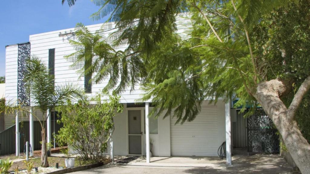 a white house with a tree in front of it at Quirky and Captivating Kurra in Hawks Nest