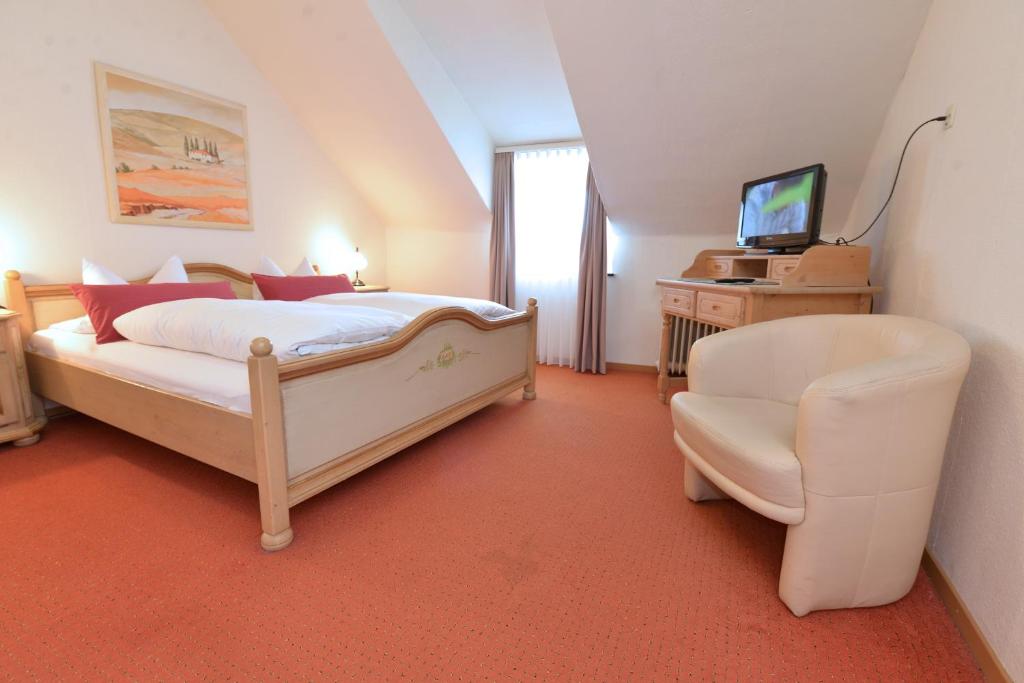 a bedroom with a bed and a chair and a television at Hotel-Restaurant "Zum Alten Fritz" in Mayen