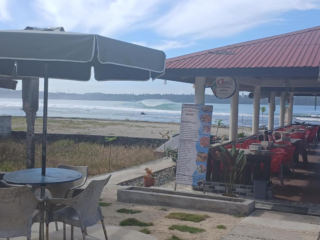 a restaurant with tables and chairs and the beach at KeyHole Surf Camp in Lagudri