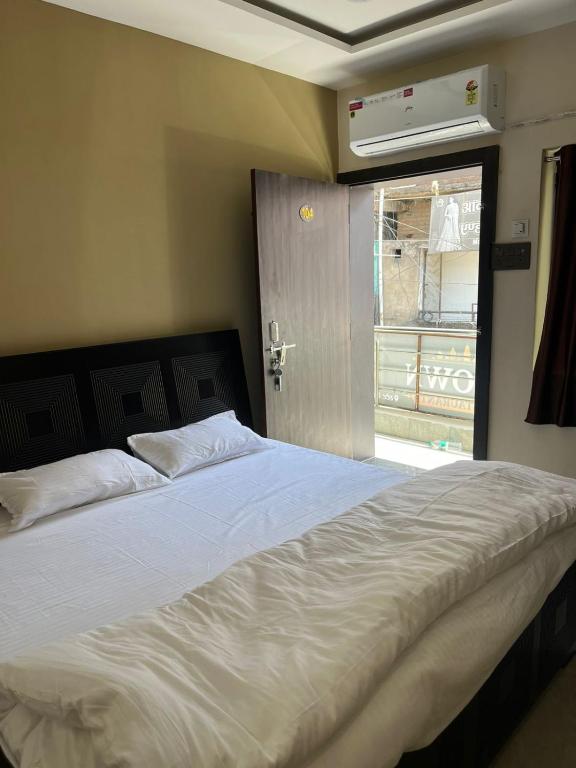 a bedroom with a white bed with a window at DownTown INN in Manendragarh