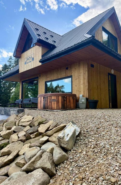 a building with a hot tub and rocks in front of it at Dom z Widokiem na Tatry- Luxury Chalet in Klikuszowa