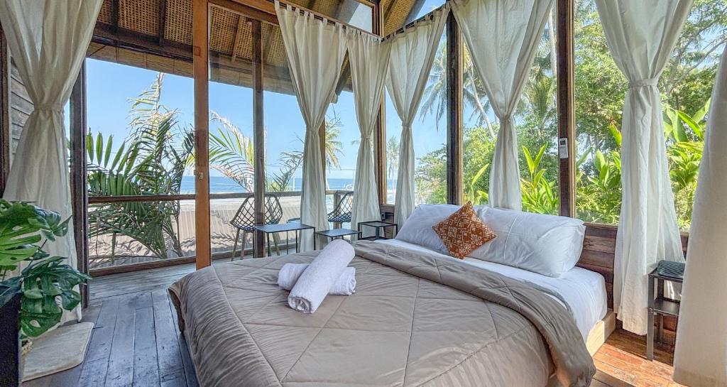 a bedroom with a bed with a view of the ocean at Salty Cabin Sunset Views Yeh Leh Beach in Balian