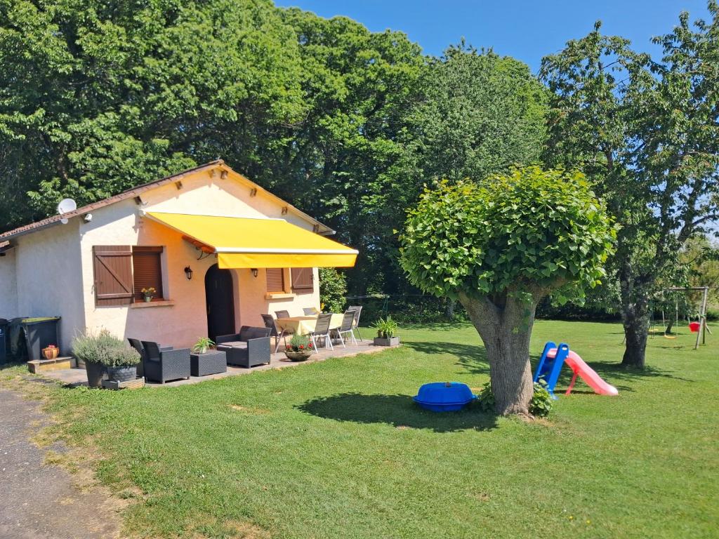 a house with a yellow umbrella and a tree at Maison de vacances en Corrèze in Saint-Pardoux-lʼOrtigier