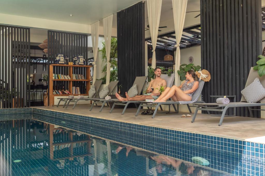 a group of people sitting next to a swimming pool at Monthara Angkor Residence in Siem Reap