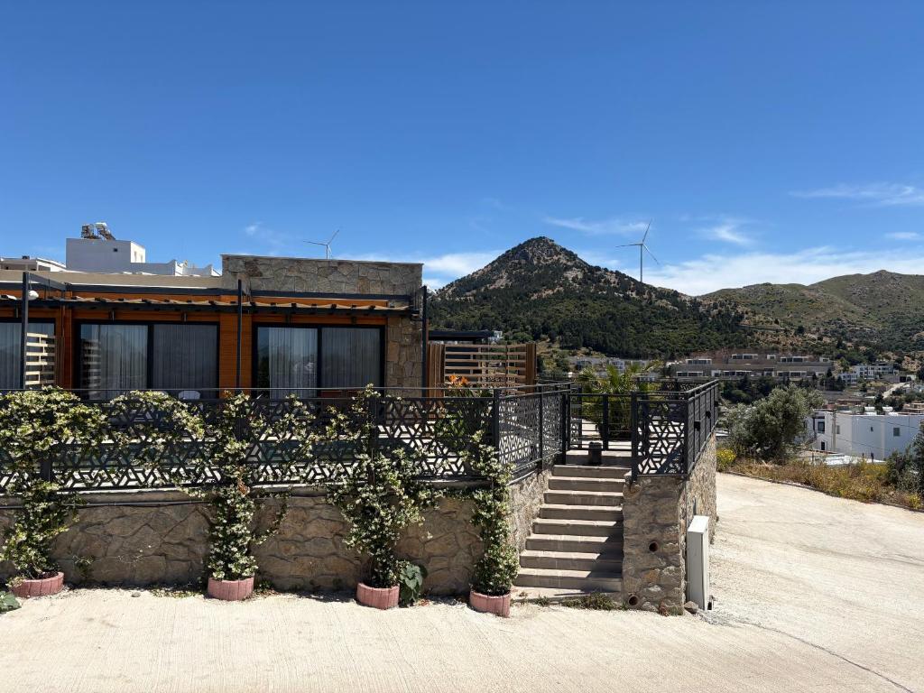 a house with a staircase and a fence with some plants at Olea Stone Houses in Bodrum City