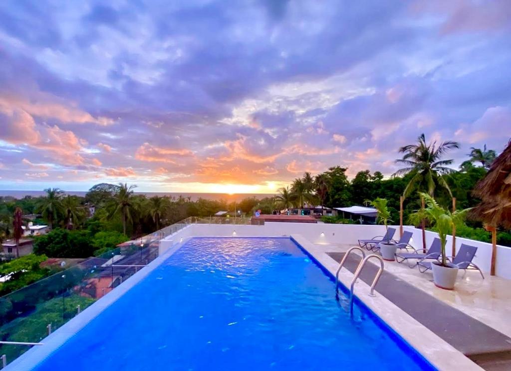 a pool with chairs and a sunset in the background at Villas Boutique Casa Ricarda in Aticama