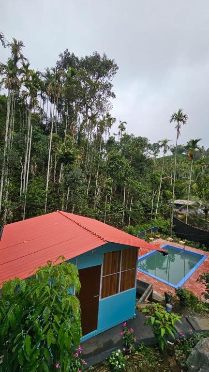 ein Haus mit rotem Dach und einem Swimmingpool in der Unterkunft Bambooleaf pool dormitory in Meppādi