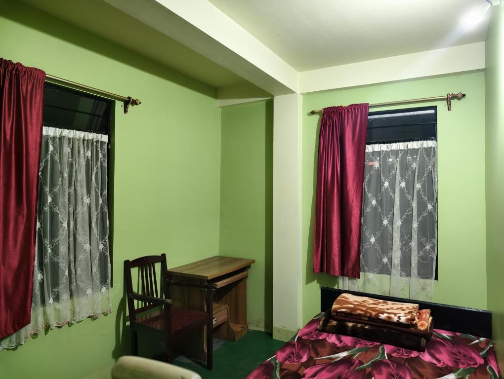 a bedroom with green walls and a chair and a desk at itynnad homestay in Shillong