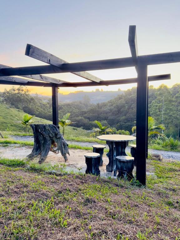 a picnic shelter with a picnic table and benches at Chalé amanhecer in Cobras