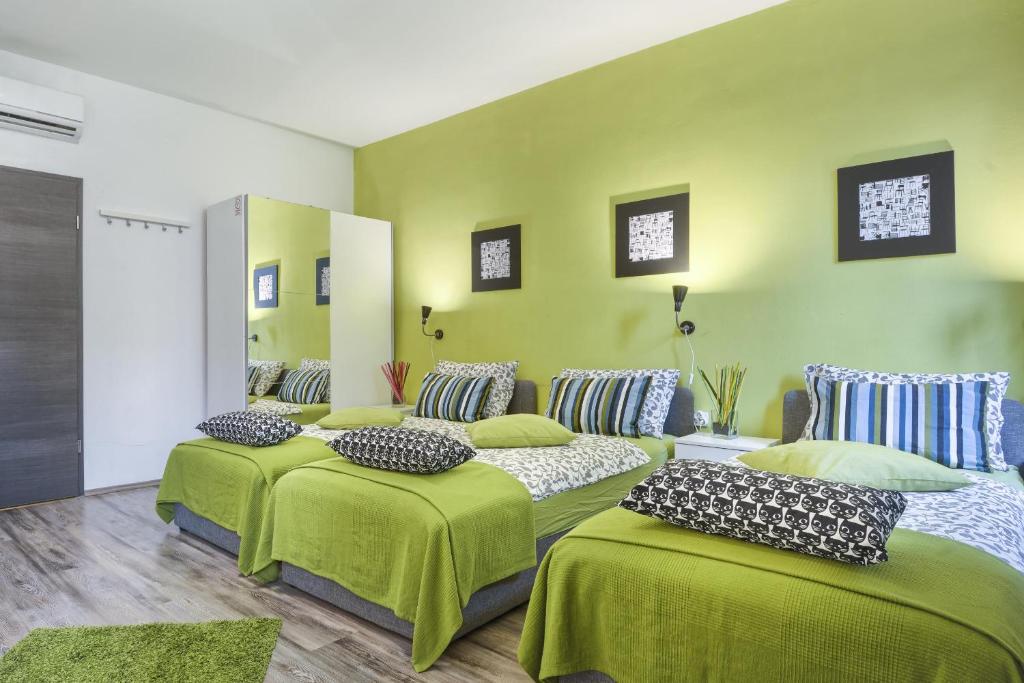 three beds in a room with green walls at Top Center Rooms & Studio in Pula