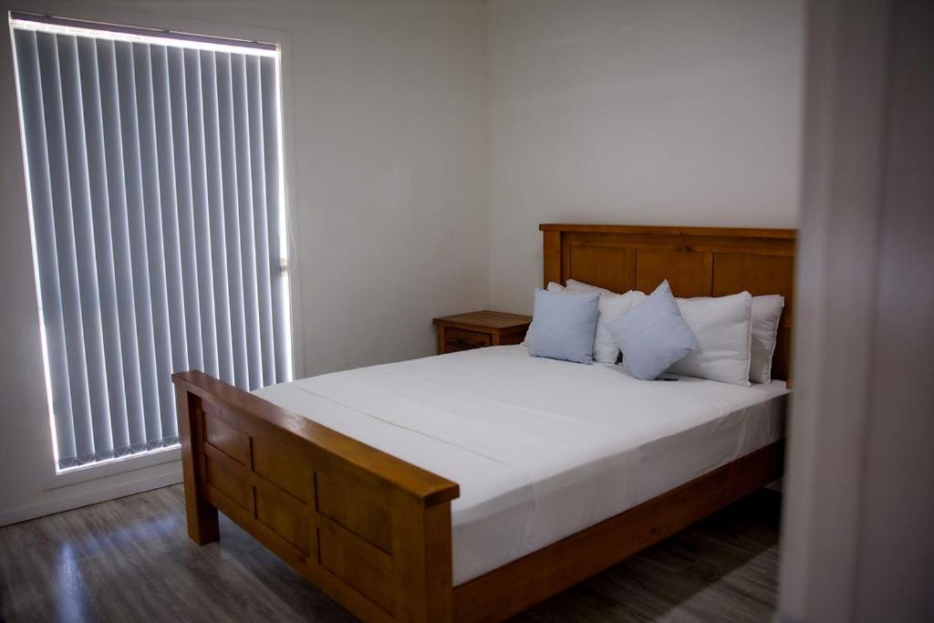 a bedroom with a bed with white sheets and a window at Taisia & Liku Homes in Nuku‘alofa