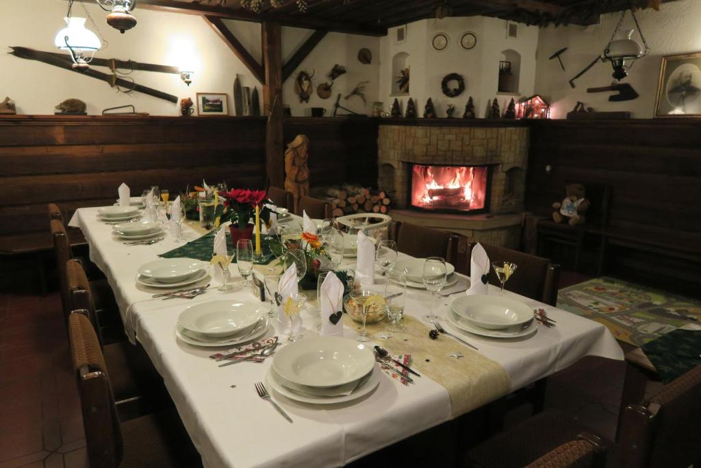a long table with white plates and glasses and a fireplace at Horský pension Gendorf in Černý Dŭl