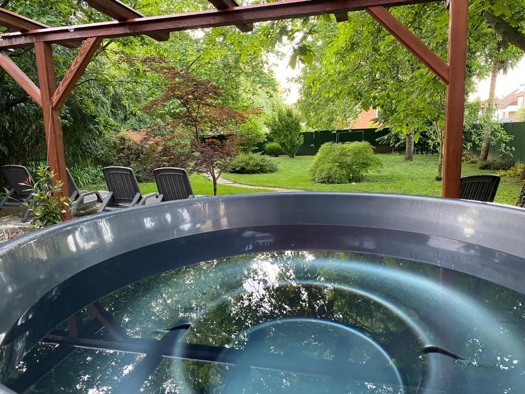 a plunge pool in a yard with chairs and a pergola at Páfrányház in Fertőd