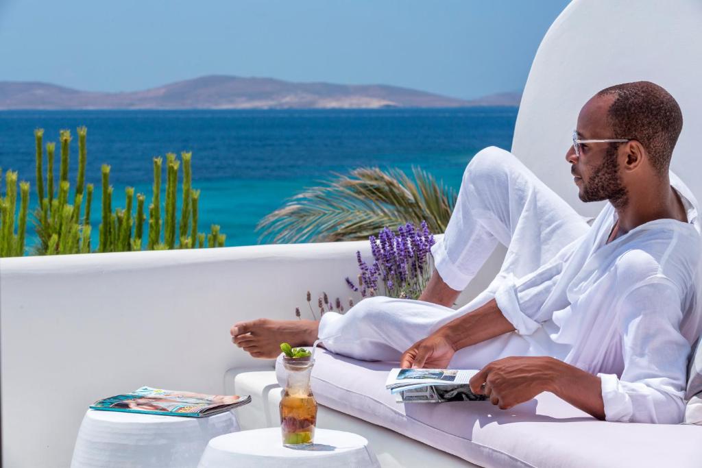 a man sitting on a couch with a book at Hippie Chic Hotel in Agios Ioannis Mykonos