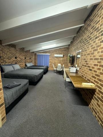 a room with two beds and a brick wall at Clock Tower Motor Inn in Coonabarabran