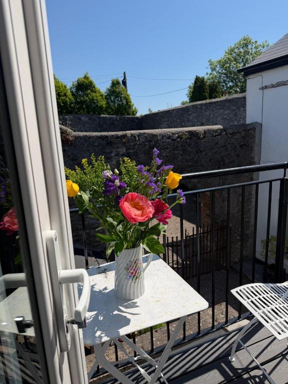 a vase of flowers sitting on a table on a balcony at The Old Parish Office! in Midleton