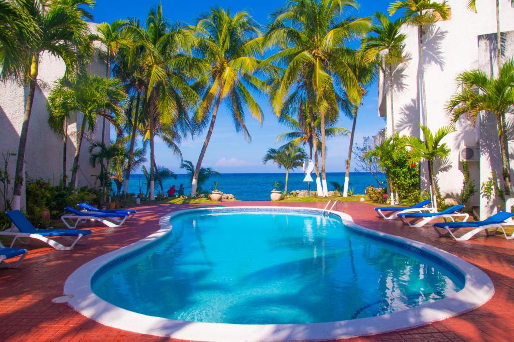 a swimming pool with palm trees and the ocean at Chrisanns Paradise Suite by the Ocean - Apt#9 in Ocho Rios