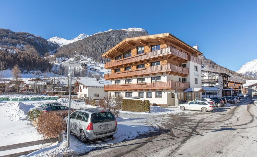 um grande edifício com carros estacionados na neve em Haus Fidelis Riml em Sölden