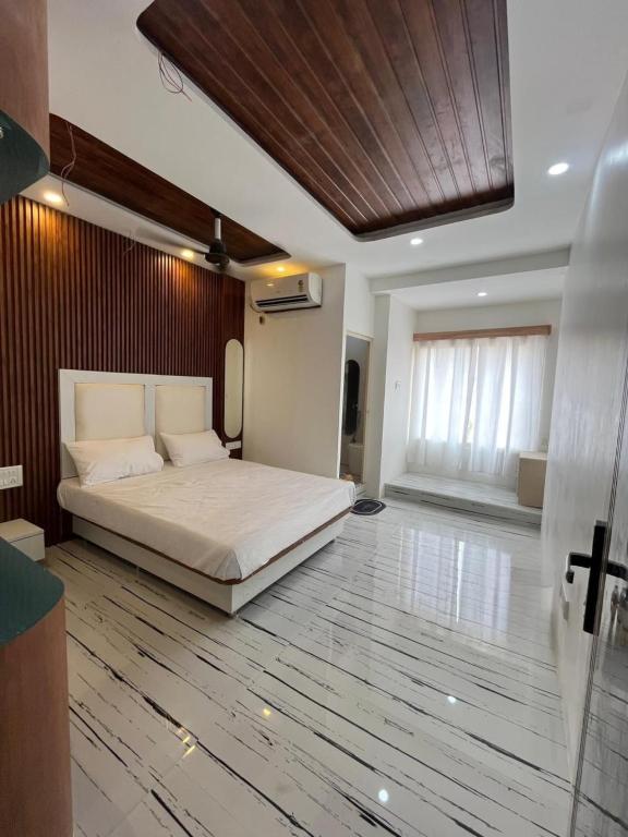 a bedroom with a large bed and a wooden floor at Hyton Grand - Kilambakkam in Urapakkam