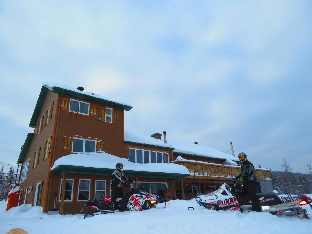 dwoje ludzi stojących w śniegu przed budynkiem w obiekcie Le Gîte Ambrelane w mieście Thetford Mines