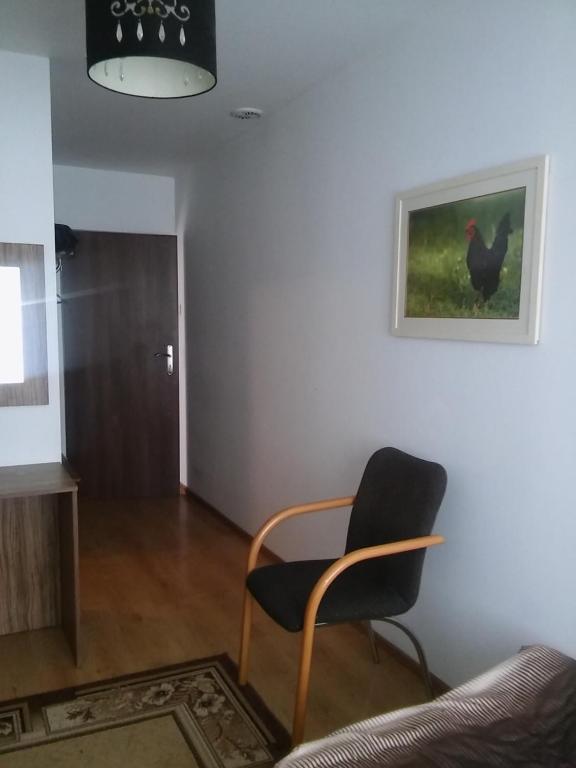 einen Stuhl in einem Wohnzimmer mit einem Bild an der Wand in der Unterkunft Pod Zachrypniętym Kogutem in Glewo