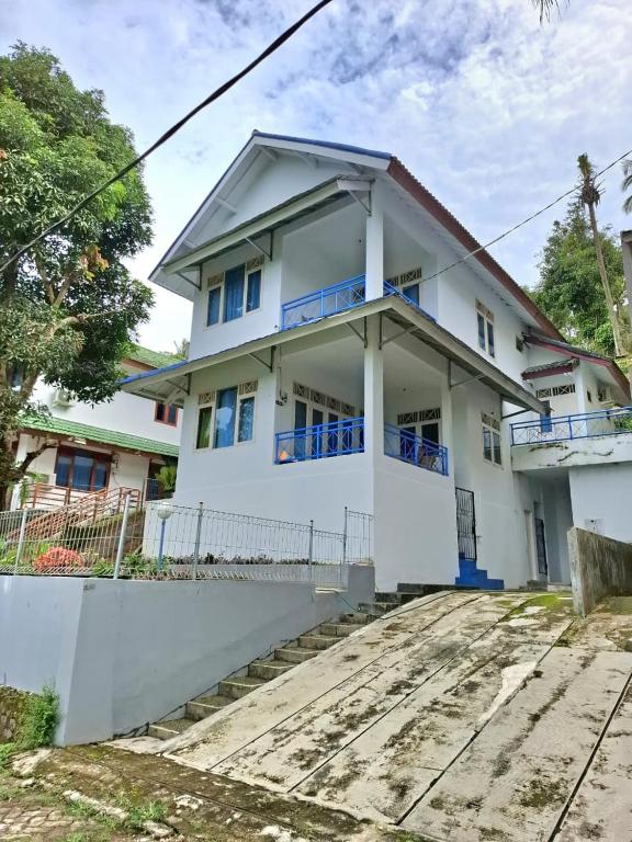 a white house with blue windows at Palm Cozy Villa 4 in Pasauran