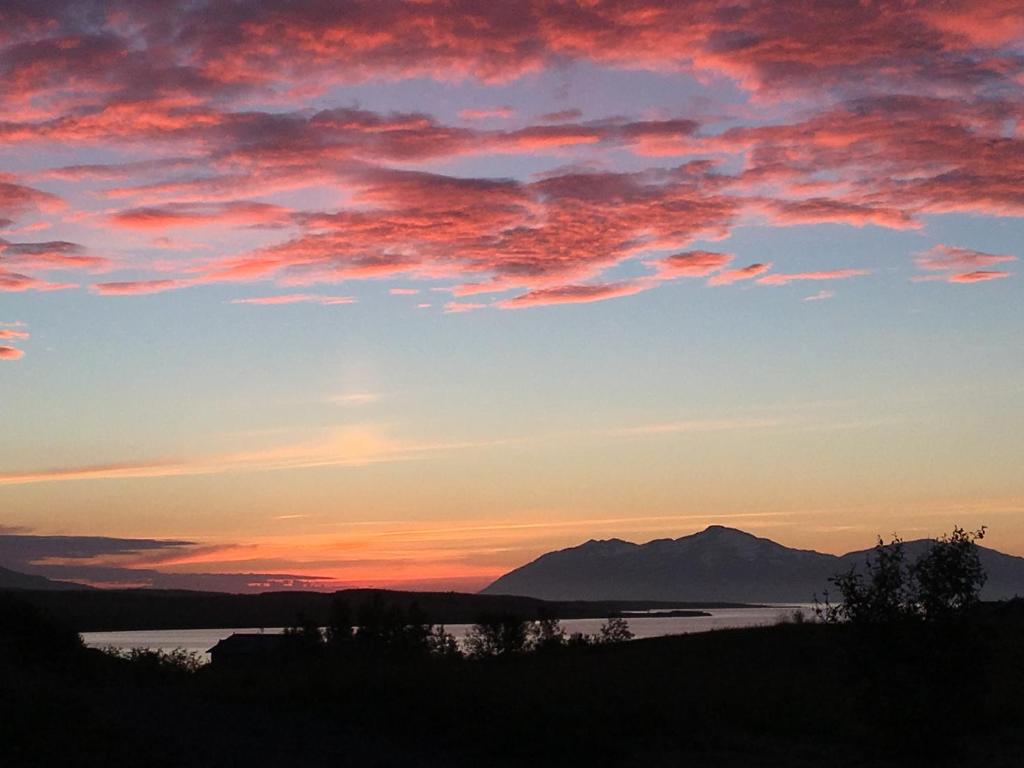einen Sonnenuntergang über einem Wasserkörper mit einem Berg in der Unterkunft Vacation Home Fagravik in Akureyri