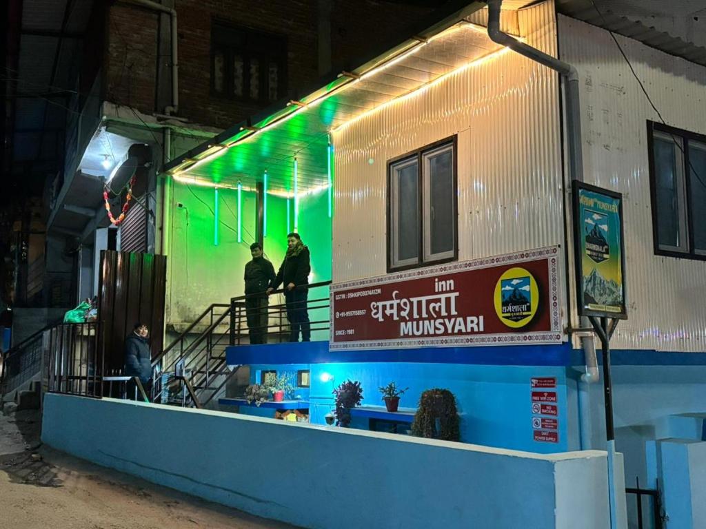three people standing on a building with green lights at DHARAMSHALA inn MUNSYARI in Munsyari