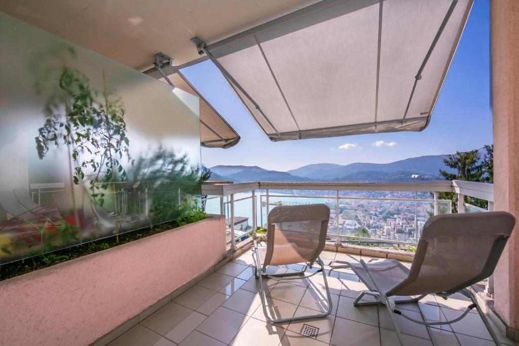 a balcony with two chairs and a view at La Maison du Bonheur with Shared Pool & Sauna - Happy Rentals in Aldesago