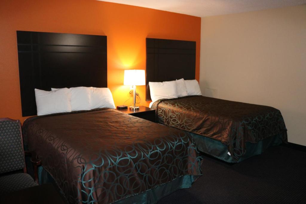 2 camas en una habitación de hotel con paredes de color naranja en Americas Best Value Inn Giddings, en Giddings