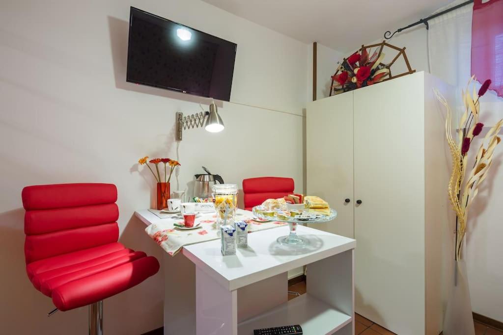 ヴェローナにあるAlle Porte Del Centroのテーブルと赤い椅子2脚が備わる客室です。