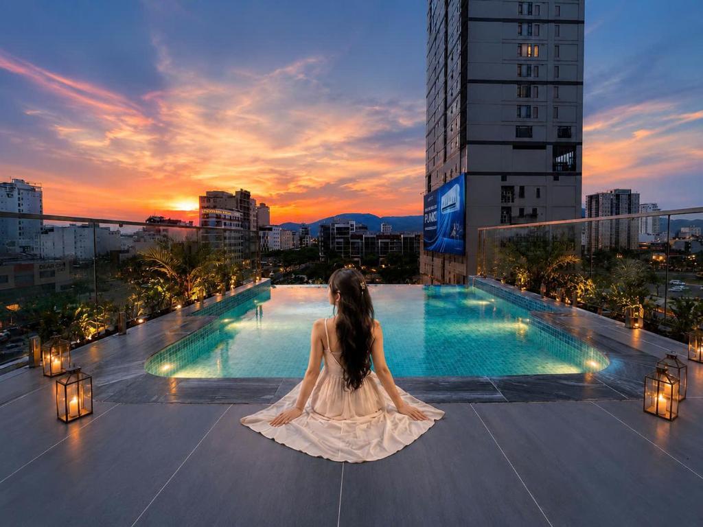 a woman in a white dress sitting on top of a building at Vista Del Sol Hotel in Danang