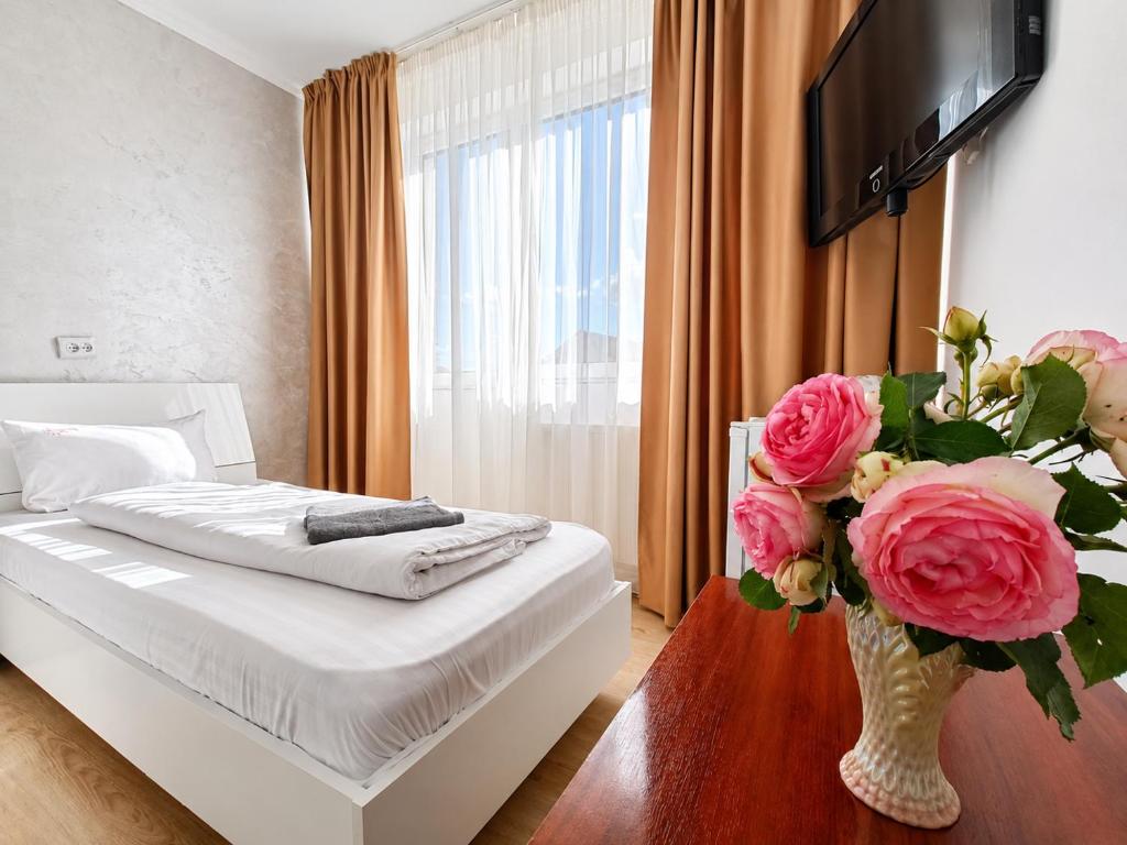 a bedroom with a bed and a vase of flowers at Pensiunea Rozeclas in Sînmartin